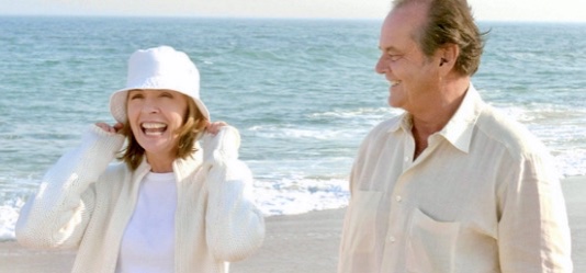 Man and woman walking on the beach smiling, waves in background